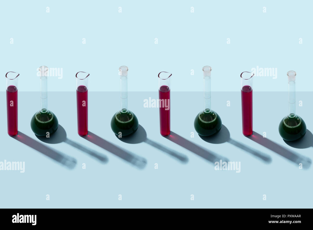 Row of test tubes with blue liquid, light blue background Stock Photo