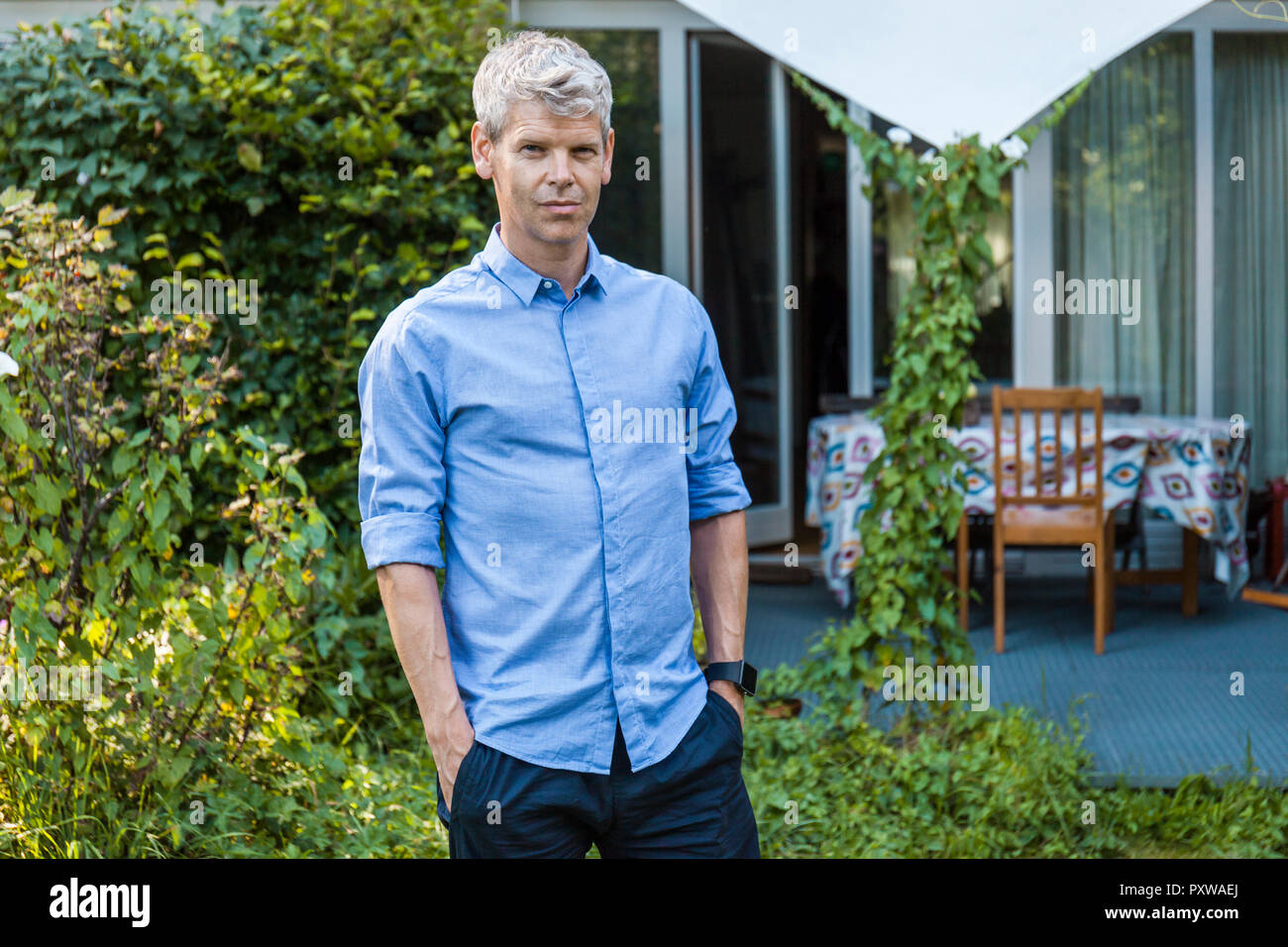 Portrait of mature man with grey hair standing in garden of his house Stock Photo