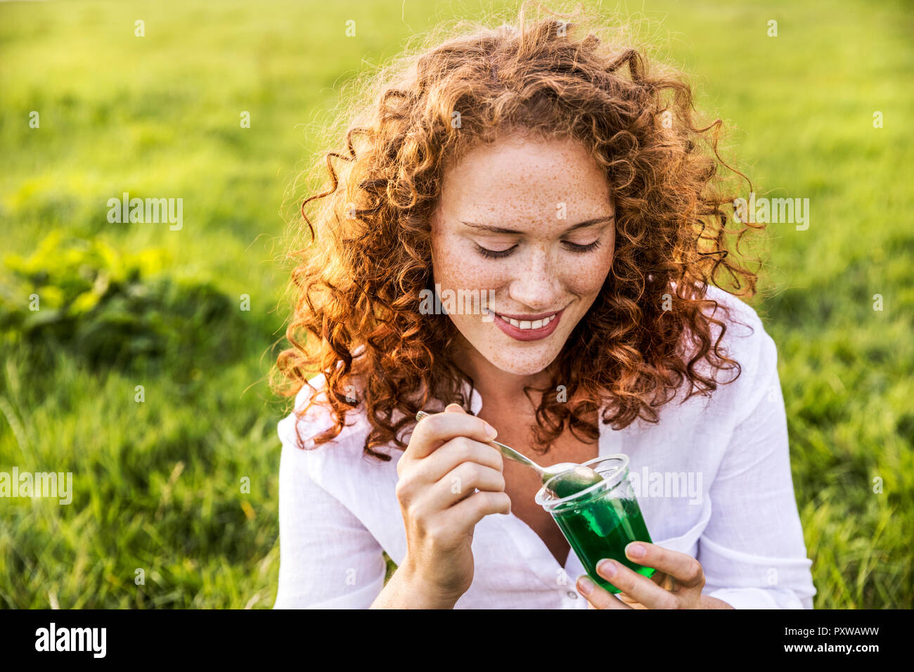 Portrait of smiling young woman eating jelly on meadow Stock Photo