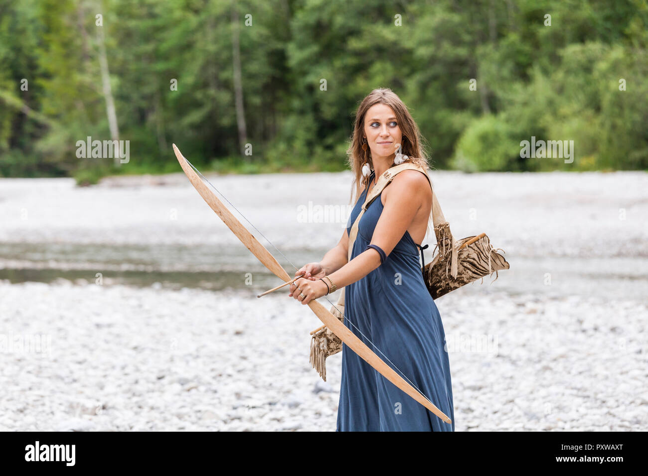 Archeress with bow and arrow in the nature Stock Photo