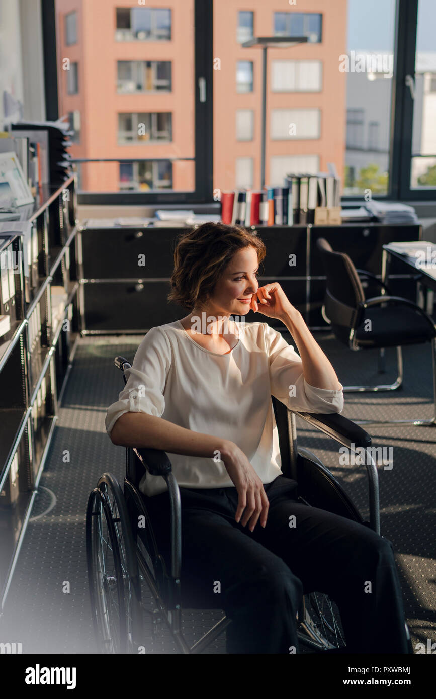 Disabled business woman sitting in wheelchair, smiling Stock Photo - Alamy