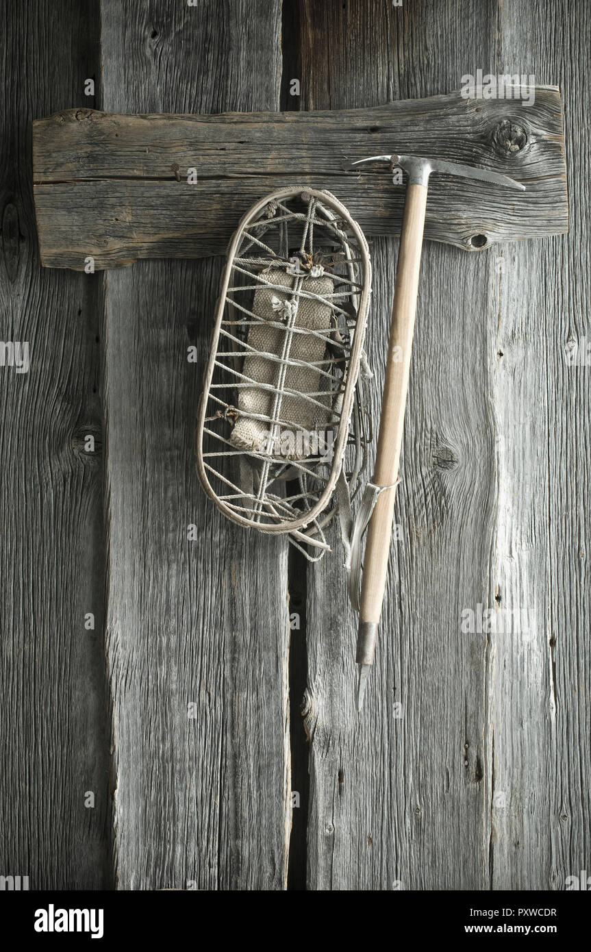 Old ice ax and snowshoes hanging on rustic wooden wall Stock Photo