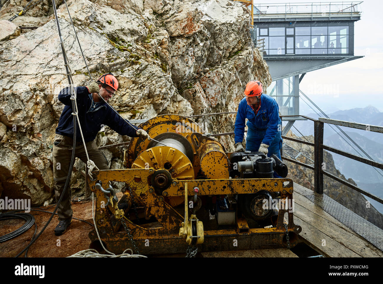 Germany, Bavaria, Garmisch-Partenkirchen, Zugspitze, installers working with rope pulley on goods cable lift Stock Photo