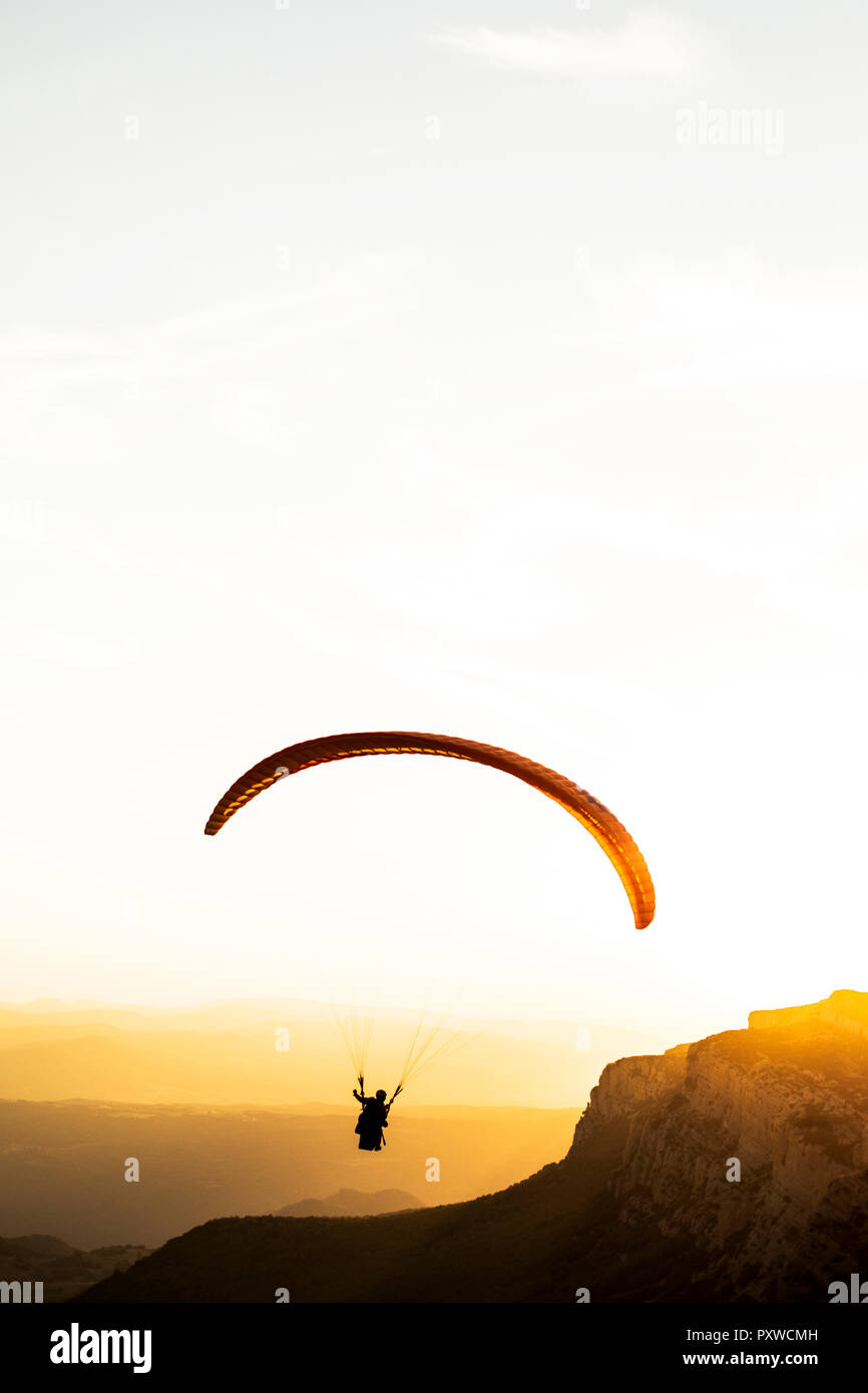 Paraglider flying, mountains in the background during sunset Stock Photo