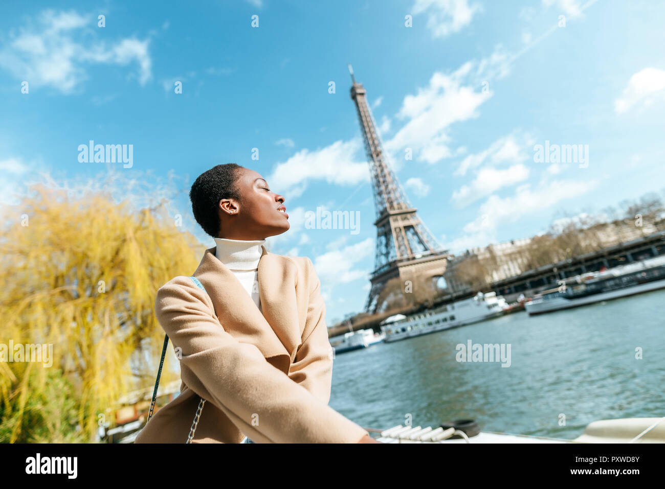 France, Paris, Woman with closed eyes at river Seine with the Eiffel Tower in the background Stock Photo