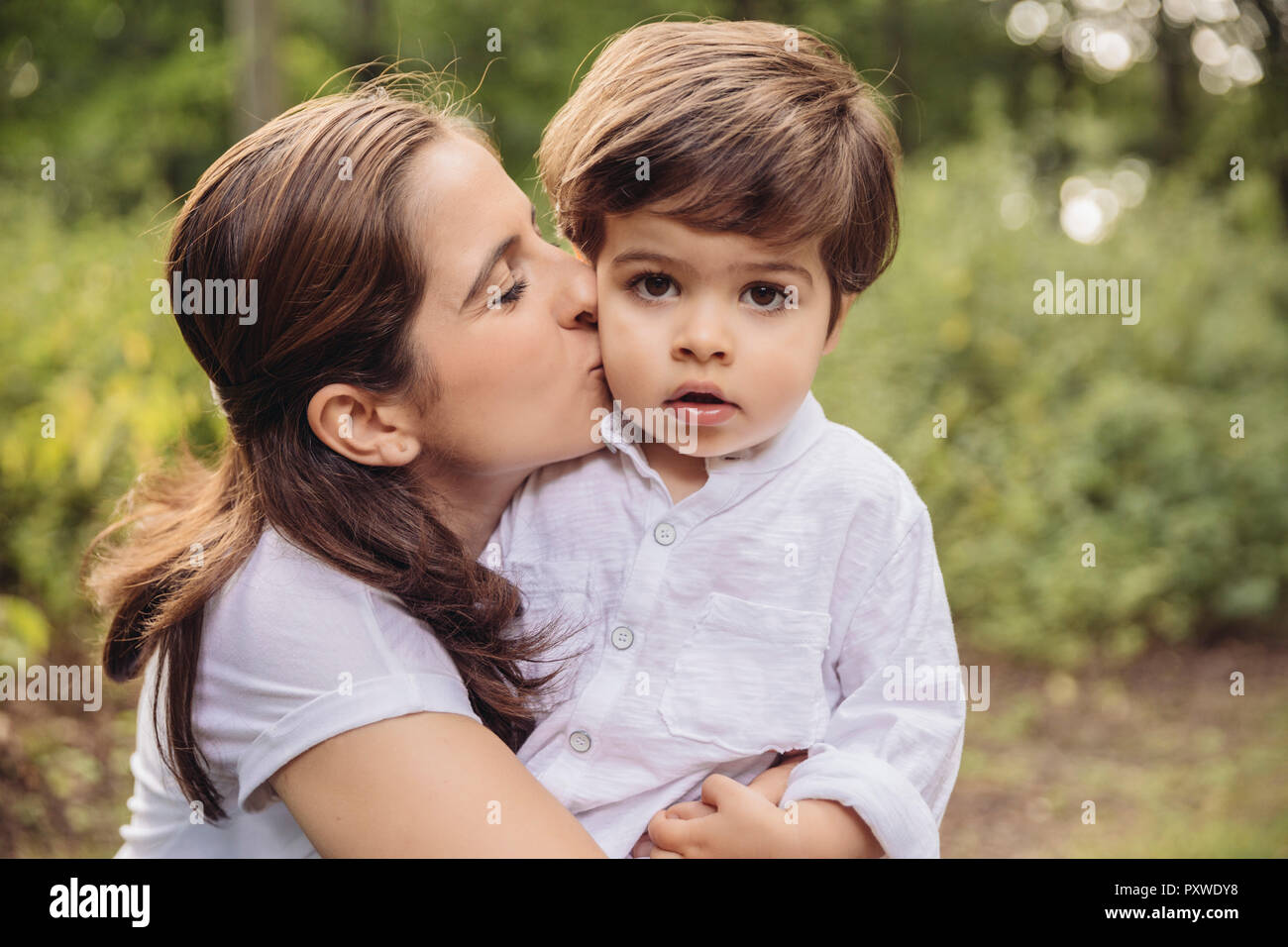 Mother kissing toddler on cheek in park Stock Photo