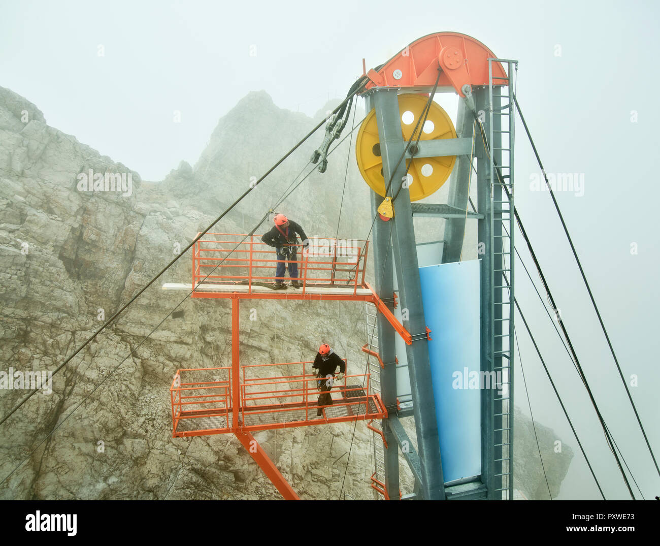 Germany, Bavaria, Garmisch-Partenkirchen, Zugspitze, installers working with rope pulley on goods cable lift Stock Photo