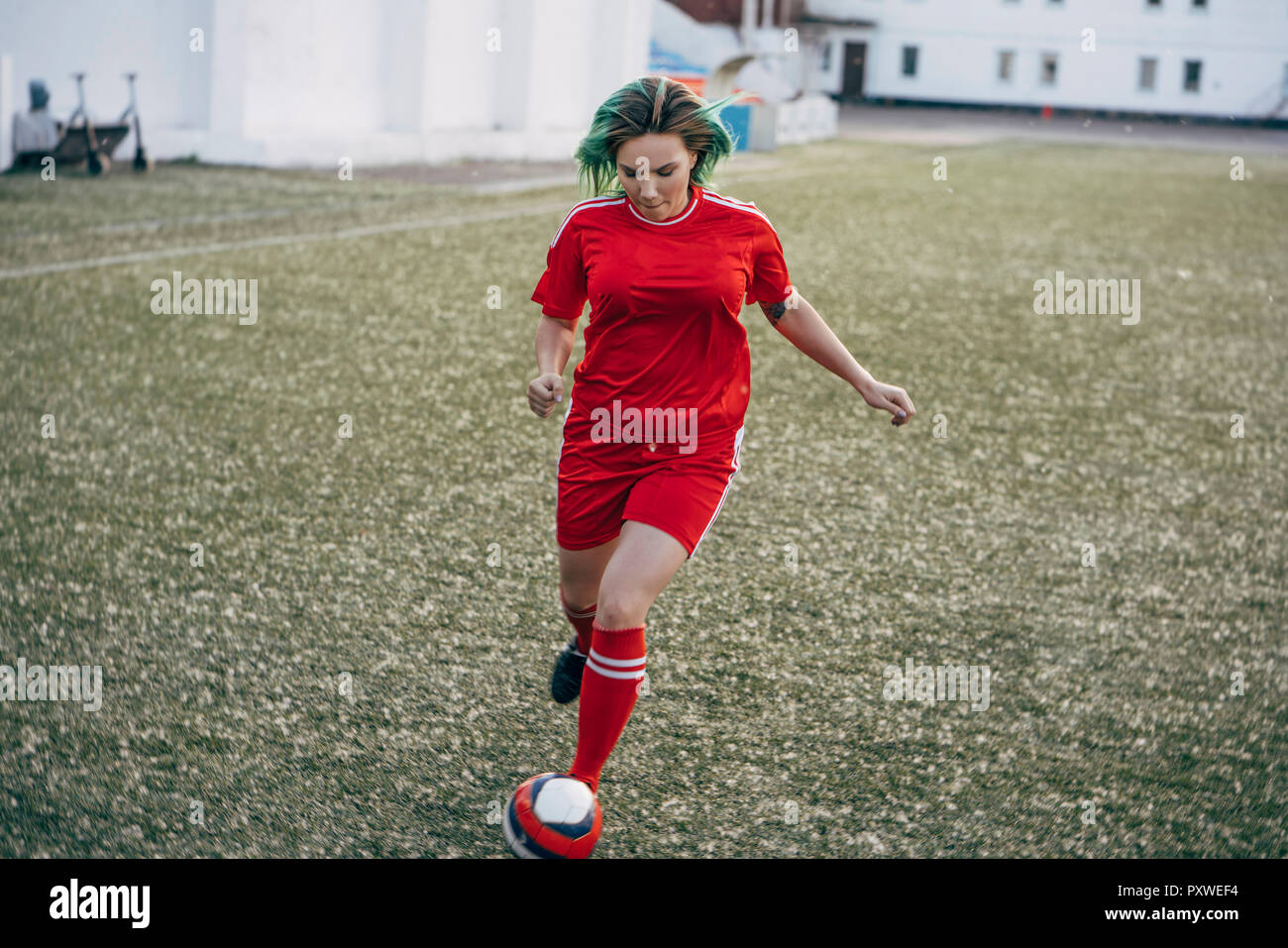 Young woman playing football on football ground running with the ball Stock Photo