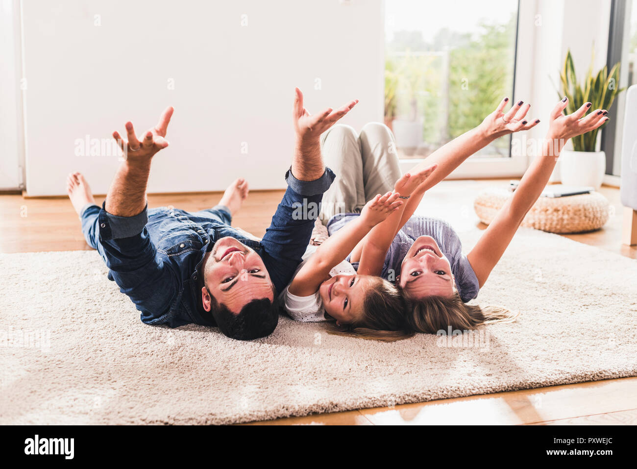 Happy family lying on carping with arms in the air Stock Photo