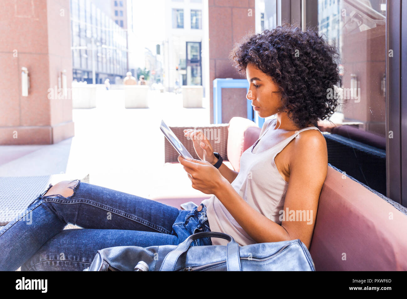 Young woman sitting at sidewalk cafe using digital tablet Stock Photo
