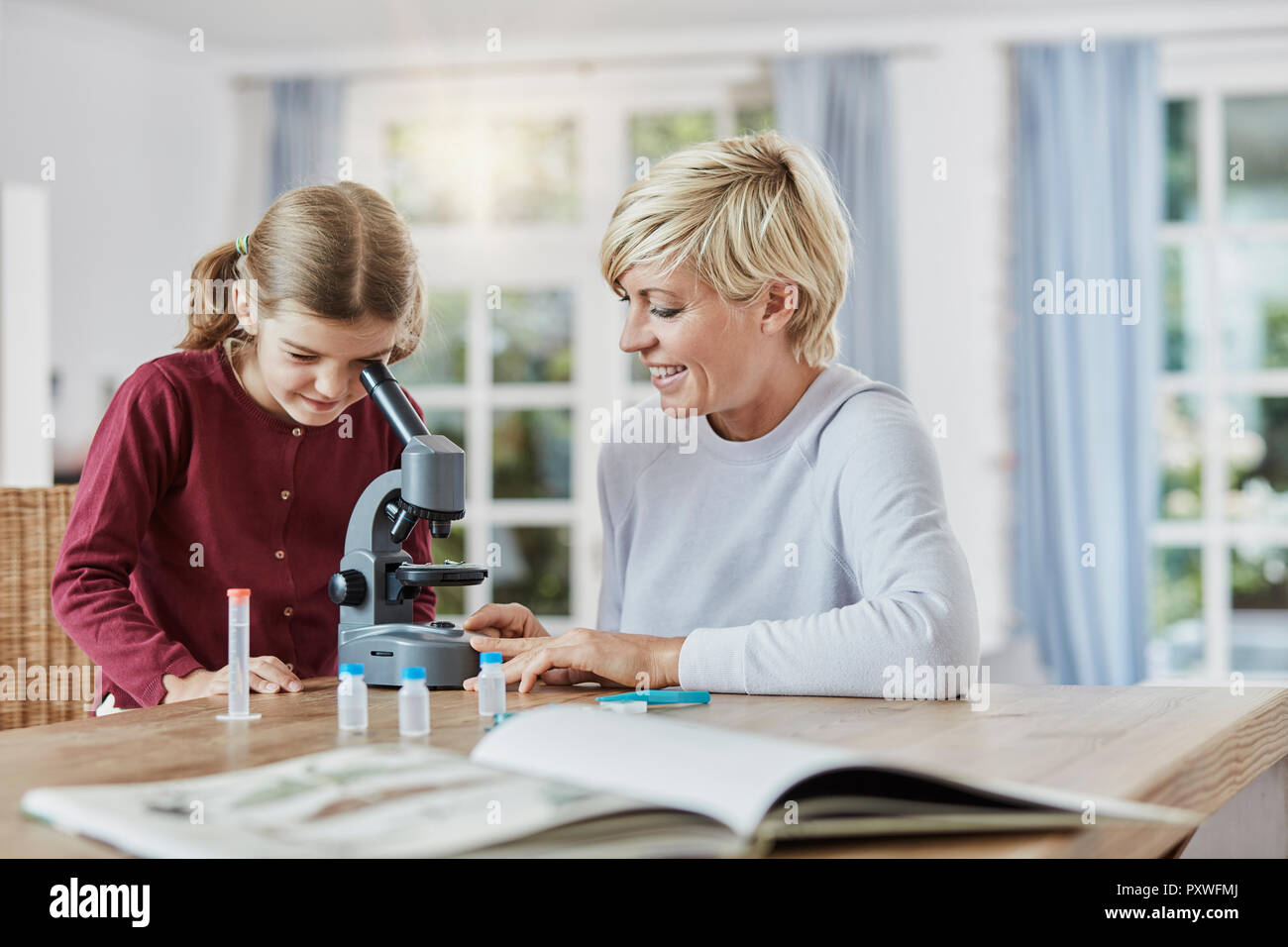 Mother and daughter using microscope at home Stock Photo