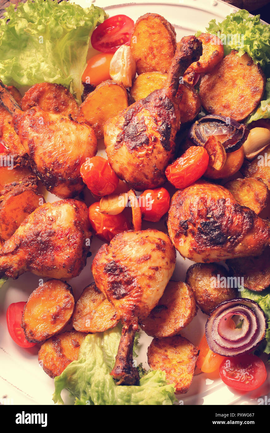 Vintage baked crispy chicken drumstick on white plate, close up view Stock Photo