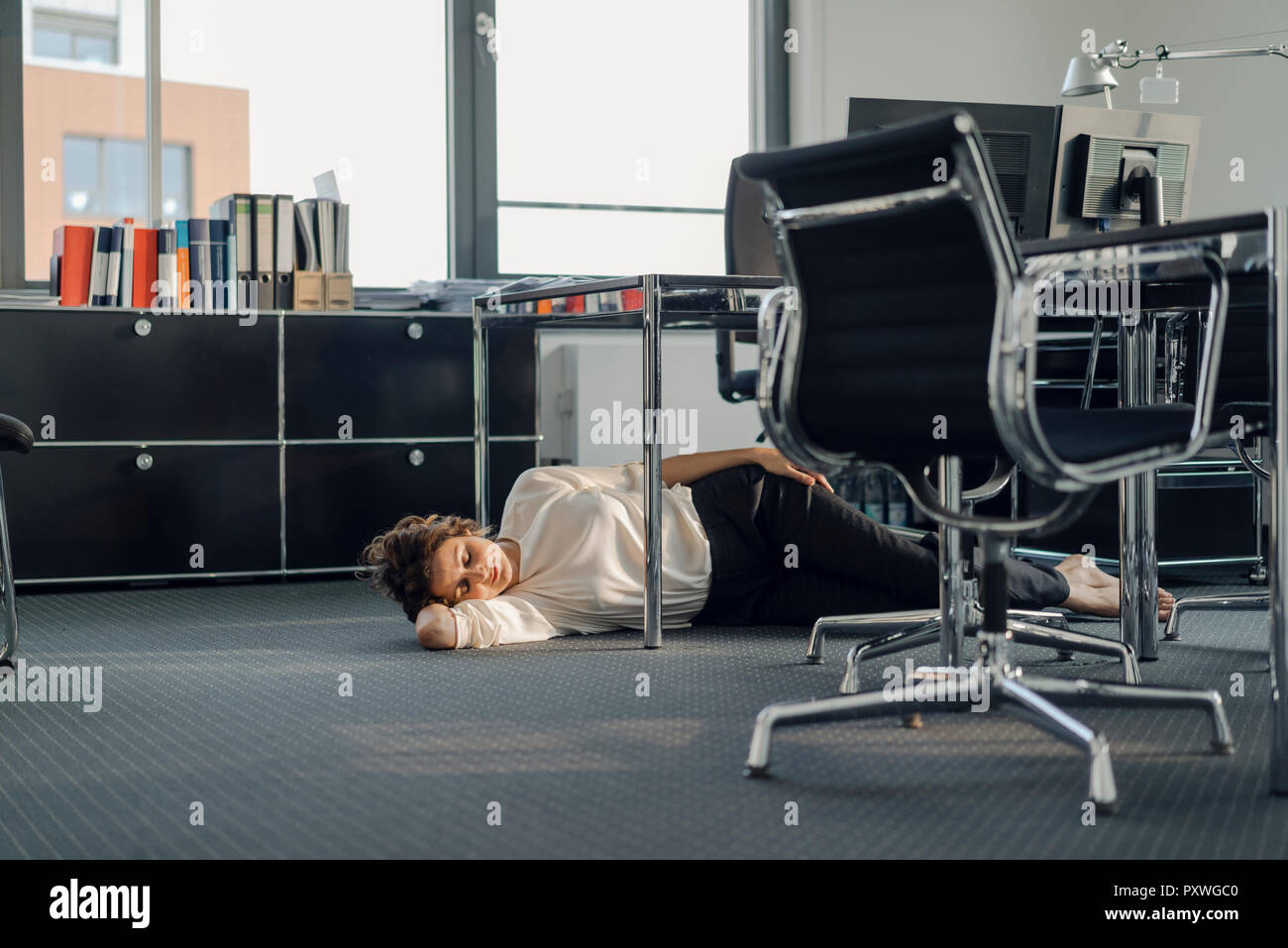 Tired businesswoman sleeping on floor under her desk Stock Photo Alamy
