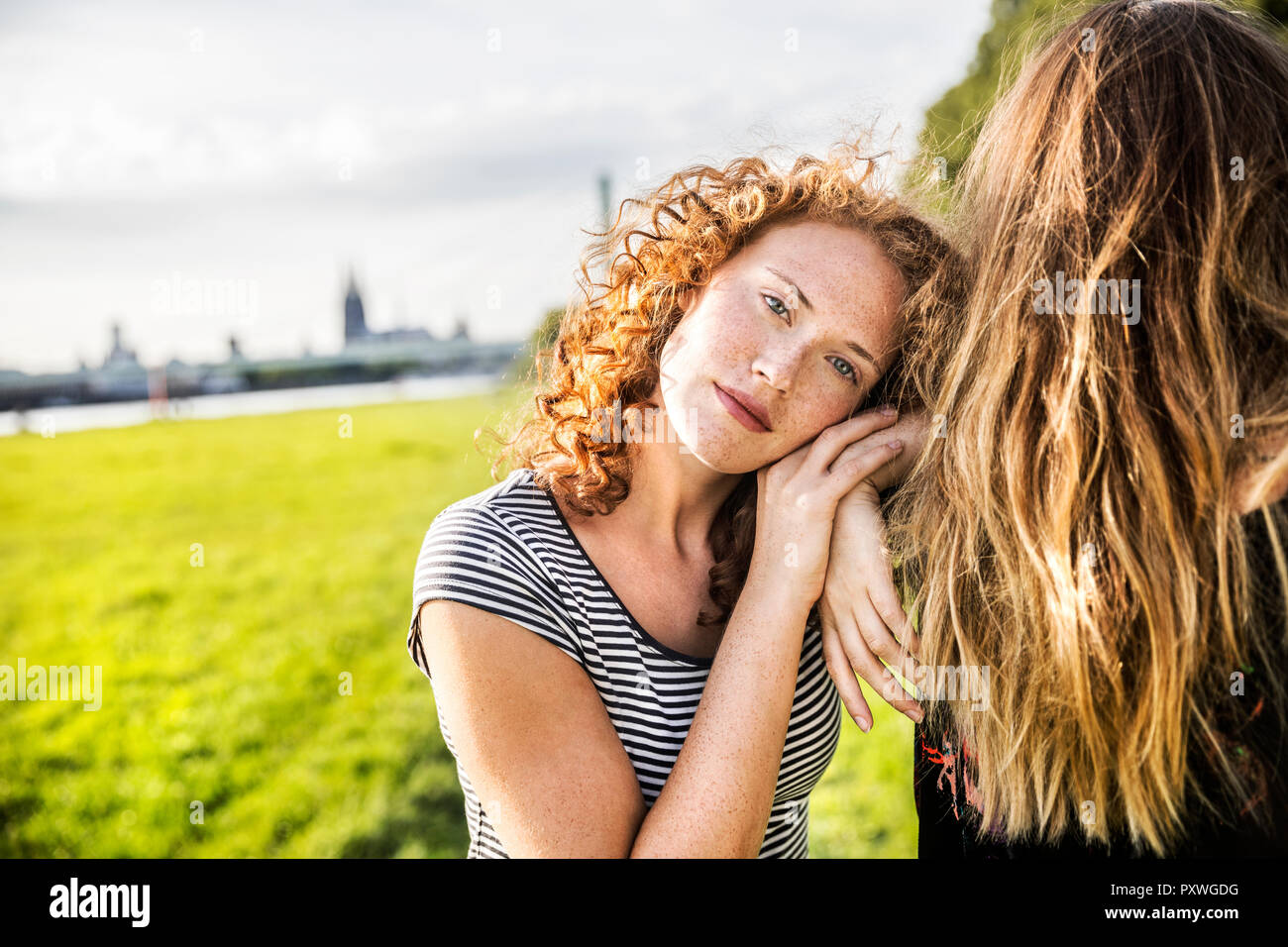 Germany, Cologne, portrait of redheaded young woman with friend Stock Photo