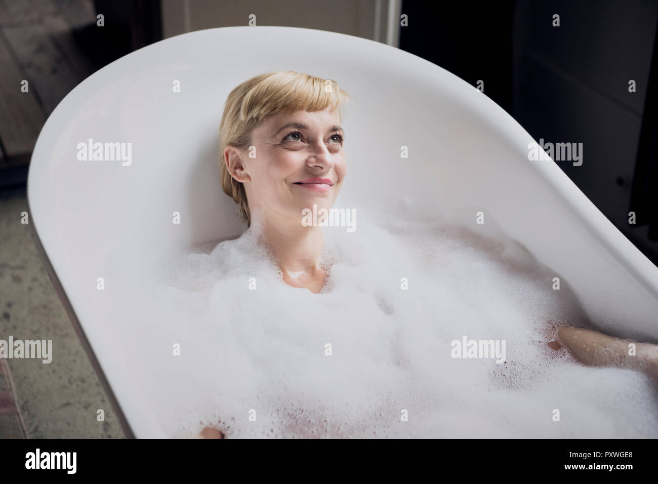 Portrait of happy woman taking bubble bath Stock Photo