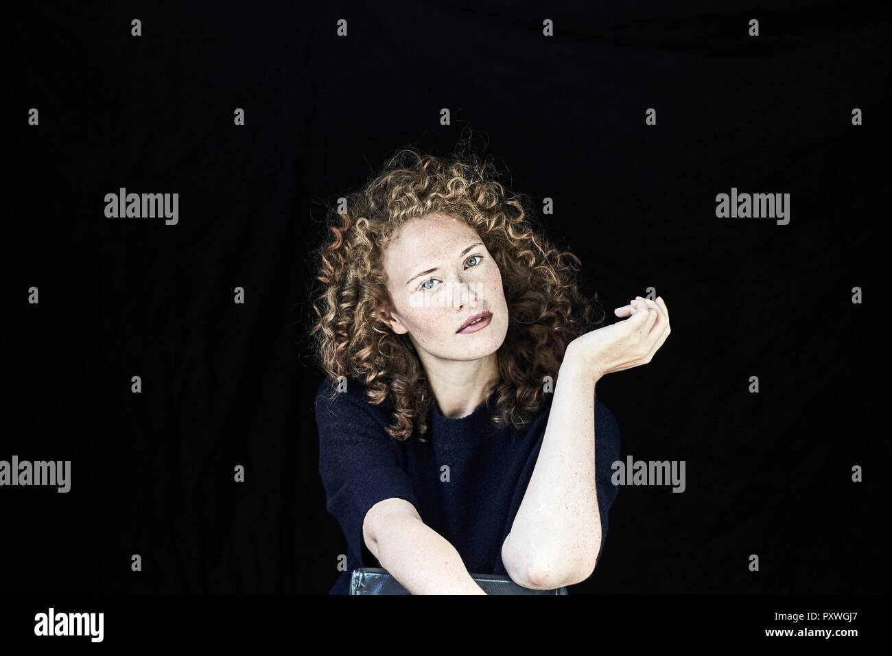 Portrait of young woman with curly  hair in front of black background Stock Photo