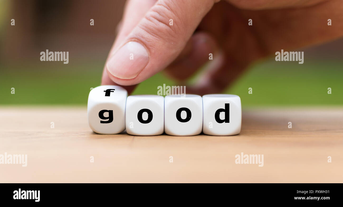 Hand is turning a dice and changes the word good to food Stock Photo