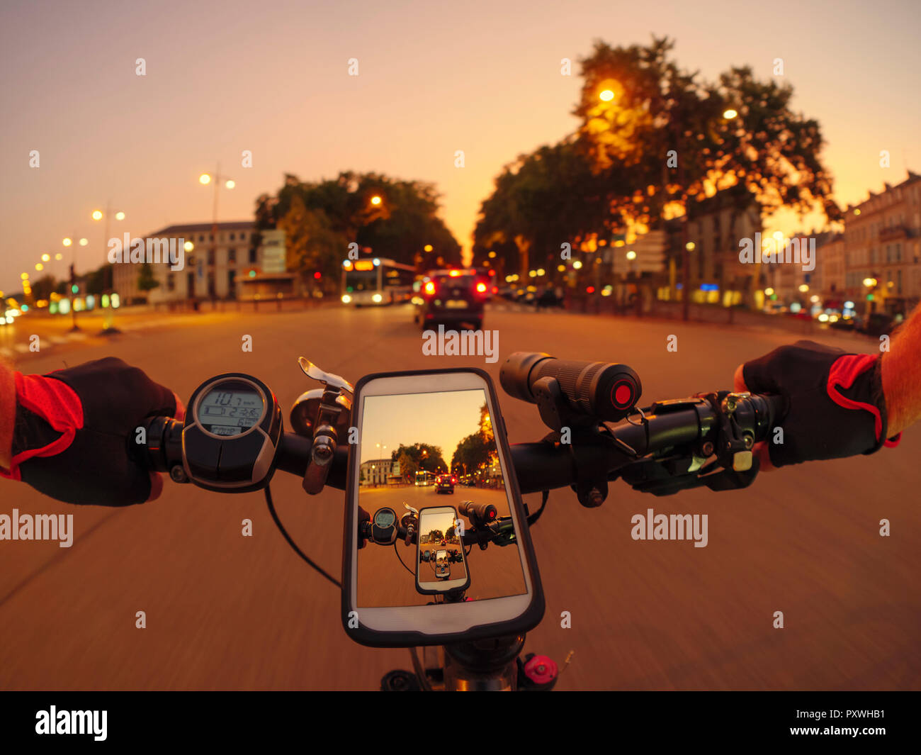 France, Versailles, personal perspective of man riding e-bike on Avenue de l'Europe at twilight Stock Photo