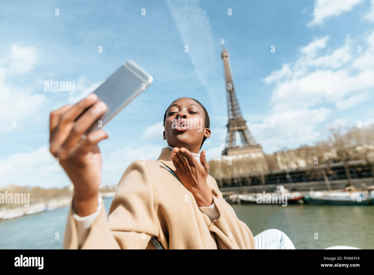 France, Paris, Woman taking a selfie with the Eiffel tower in the background Stock Photo