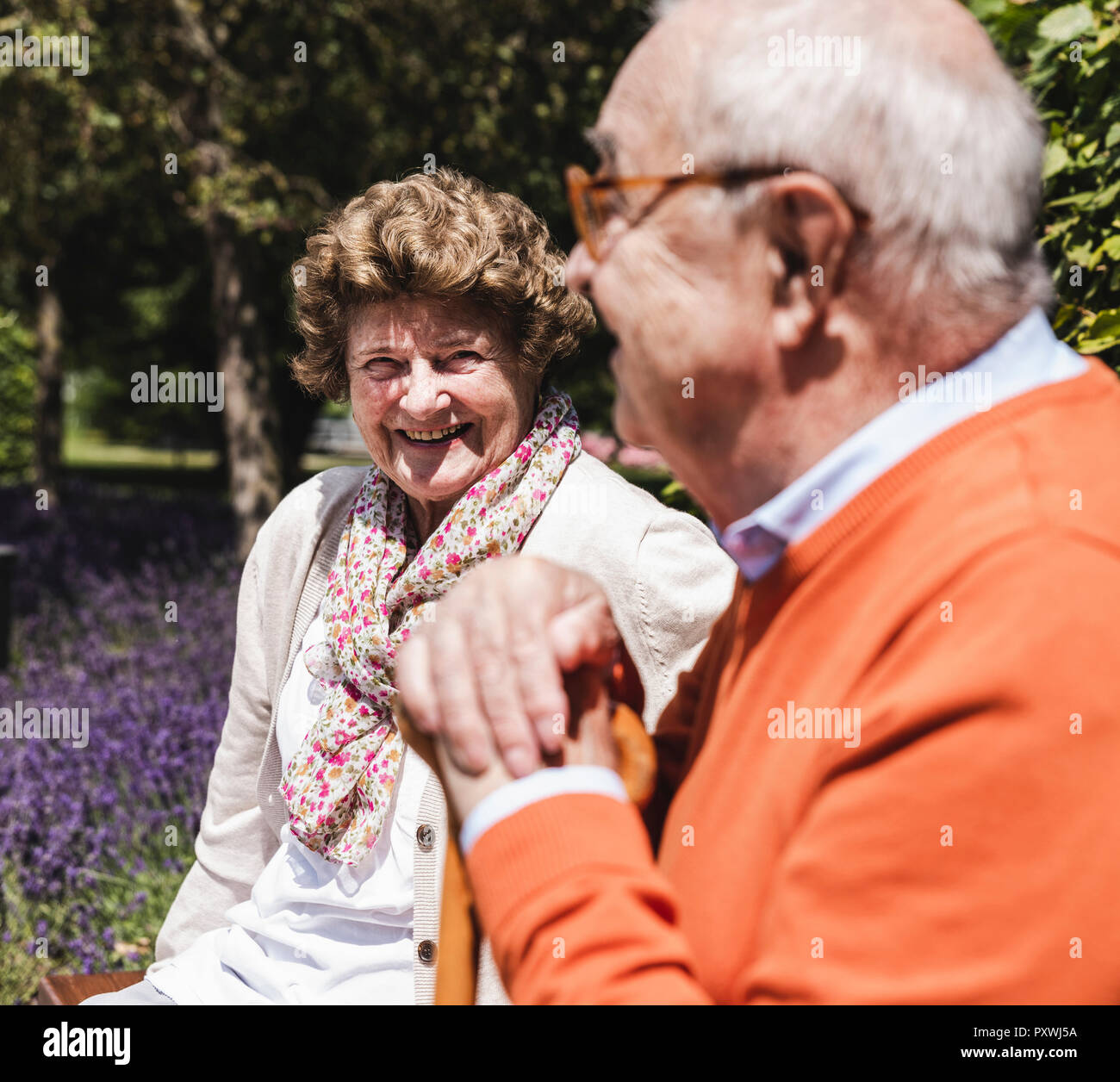 Senior couple sitting on bench in a park, talking Stock Photo