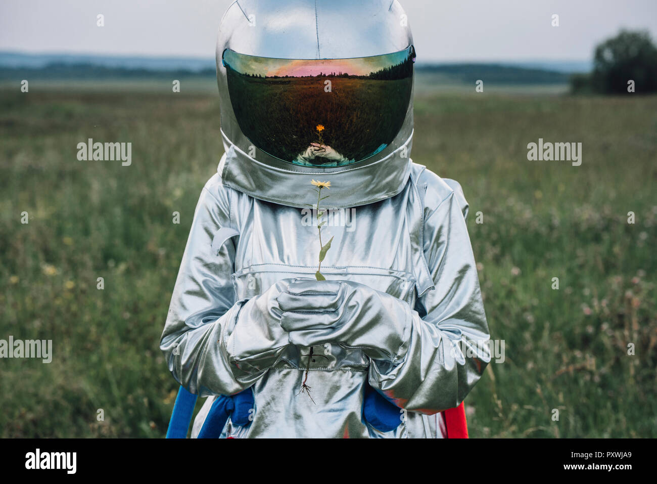 Spaceman holding flower, watching it grow Stock Photo