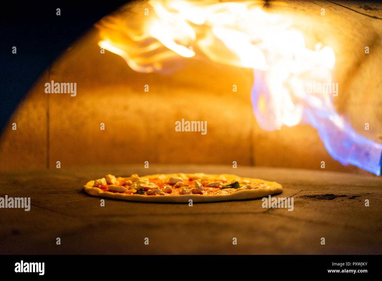 Pizza in oven with burning flame Stock Photo