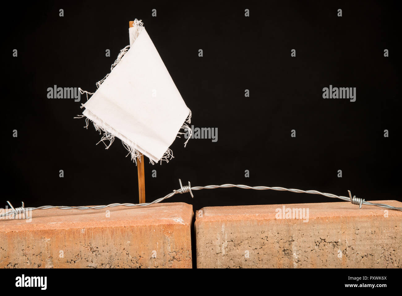 White flag on a wall, a multiple concept both on overworking and on immigration Stock Photo