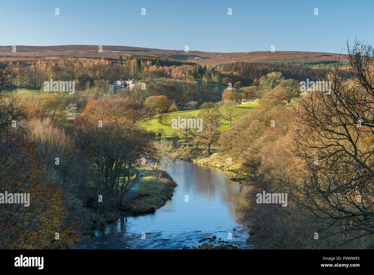 Sunny autumn high view over scenic River Wharfe, looking upstream to Barden Tower ruins & blue sky - Bolton Abbey Estate, Yorkshire Dales, England, UK Stock Photo