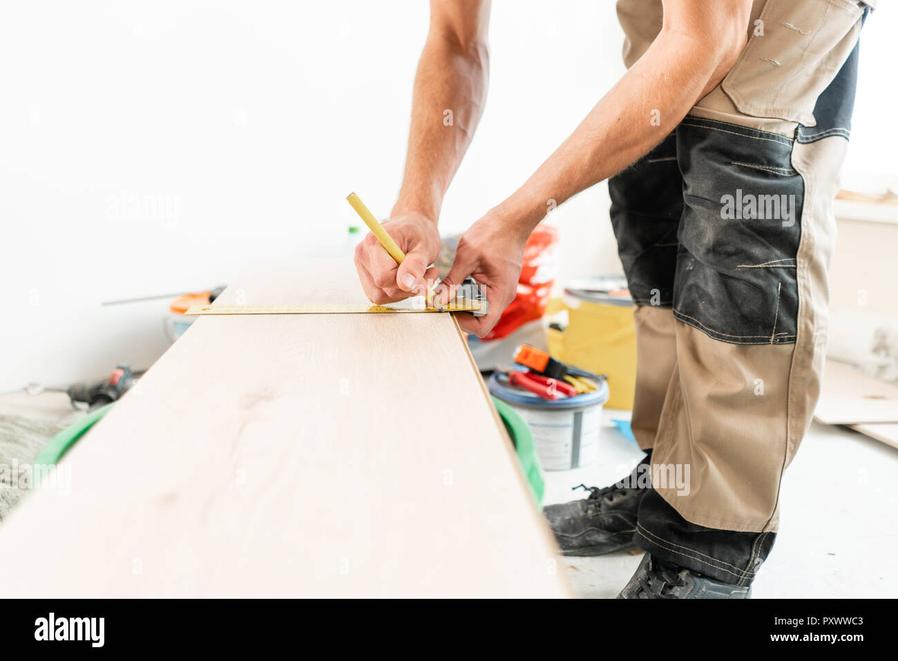 Male Worker Applies Markings To The Board For Cutting With A