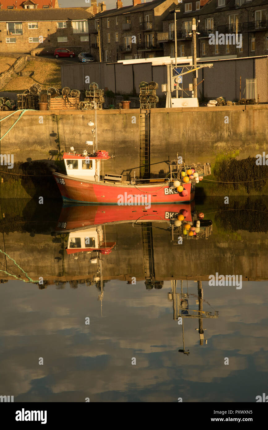 Reflection of a fishing boat in Seahouses harbour, Northumberland, England Stock Photo
