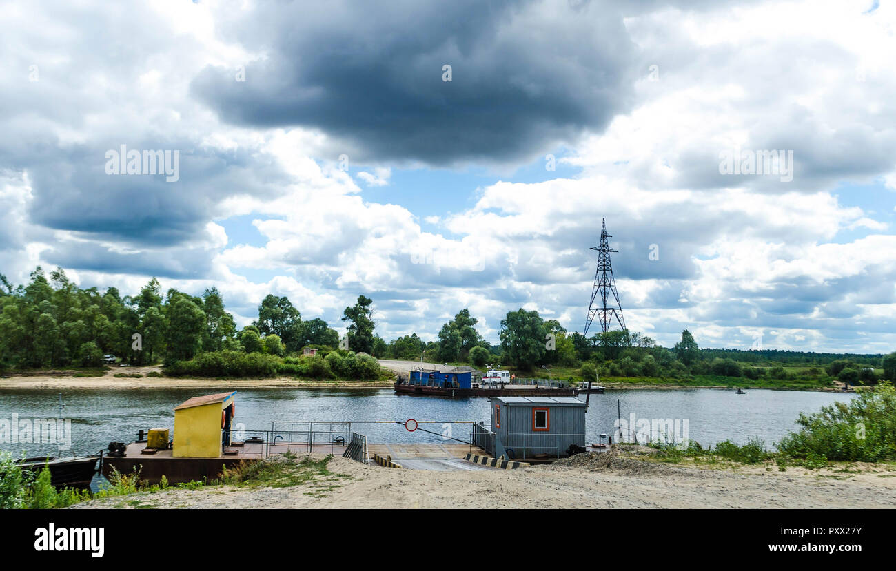 View of the Pripyat River on a background of blue sky and white clouds. Ferry service for the transport of people, cars and goods by water Stock Photo