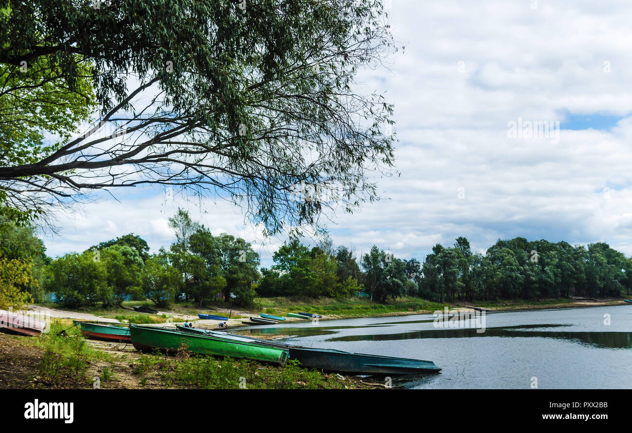 Pier with old fishing boats on the bank of the Pripyat River near the village of Petrikov village. Travel to Belarus. Water landscape Stock Photo