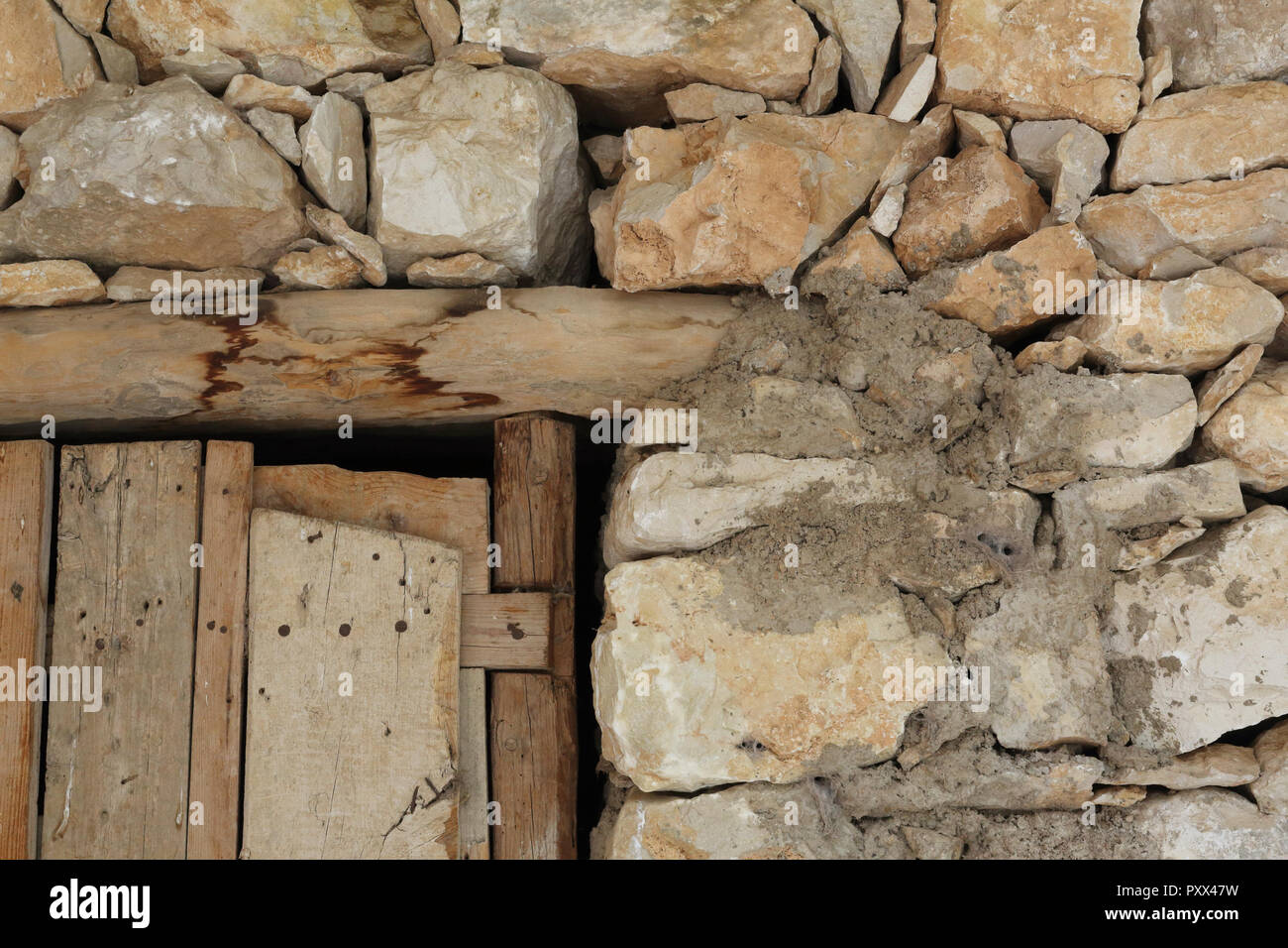 The detail of a wooden door and joint of a shelter for livestock made of stone drywall in the Barranco de la Hoz Seca canyon, Jaraba, Spain Stock Photo