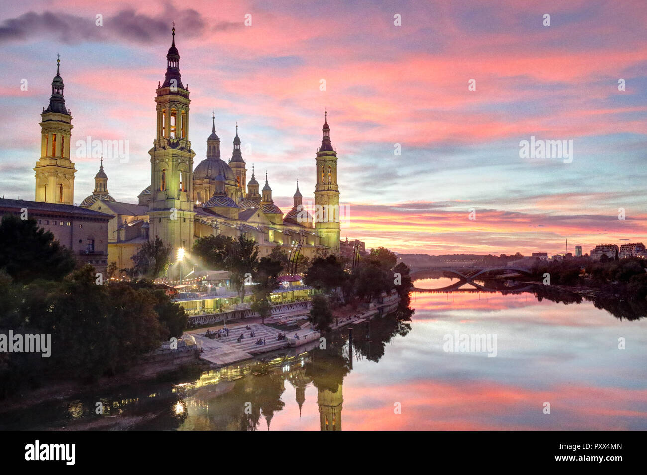 A landscape of Pilar Cathedral and Santiago Bridge reflecting in the Ebro river at sunset, after a storm, in a cloudy autumn, in Zaragoza, Spain Stock Photo