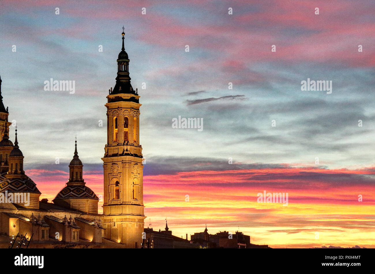 A landscape of a bell tower of the Pilar Cathedral lightened at sunset, after a storm, in a cloudy autumn, with pink clouds, in Zaragoza, Spain Stock Photo