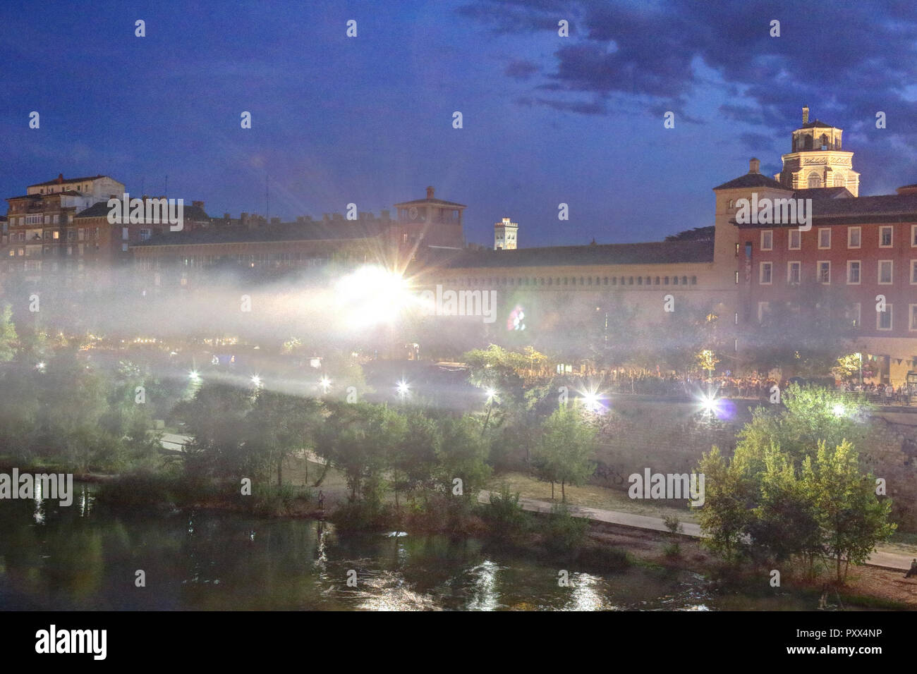 The rio Ebro and the Echegaray boulevard by night on backlight during the Pilar 2018 festival, with people eating and shopping at stands Stock Photo