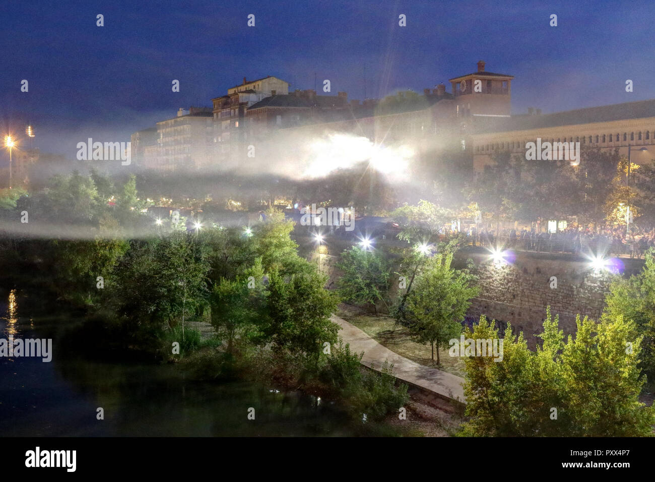 The rio Ebro and the Echegaray boulevard by night on backlight during the Pilar 2018 festival, with people eating and shopping at stands Stock Photo