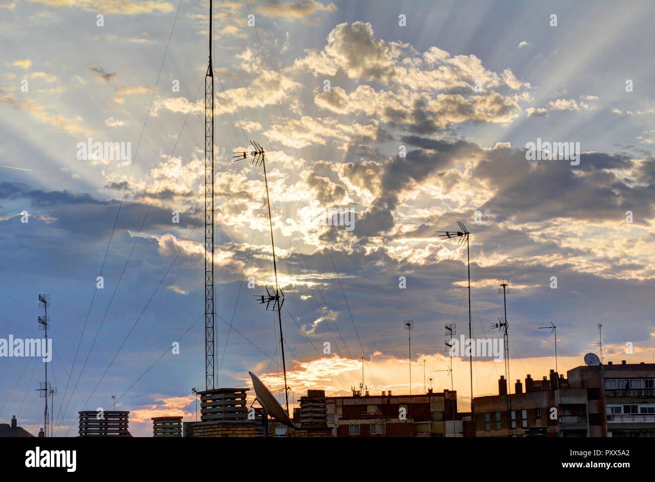 The sunbeams coming out from the pink clouds during an orange dawn on a spring morning, with the city silhouette, in Zaragoza, Spain Stock Photo