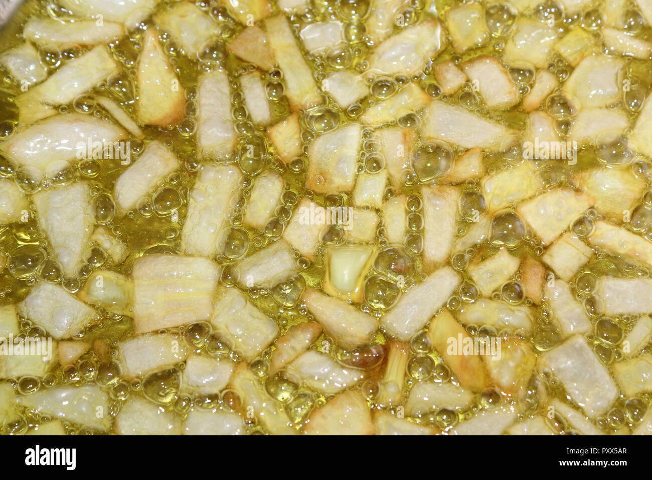 A close view of an onion sautéed being fried in virgin olive oil, with