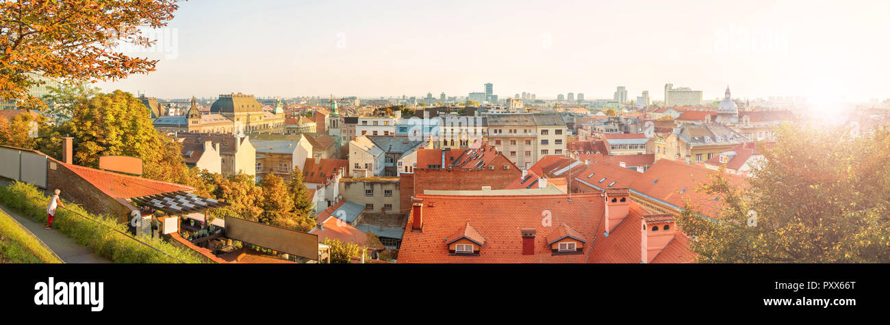 panoramic image of female tourist looking at Zagreb city center view with beautiful old buildings at sunset on warm fall day, Croatia Stock Photo