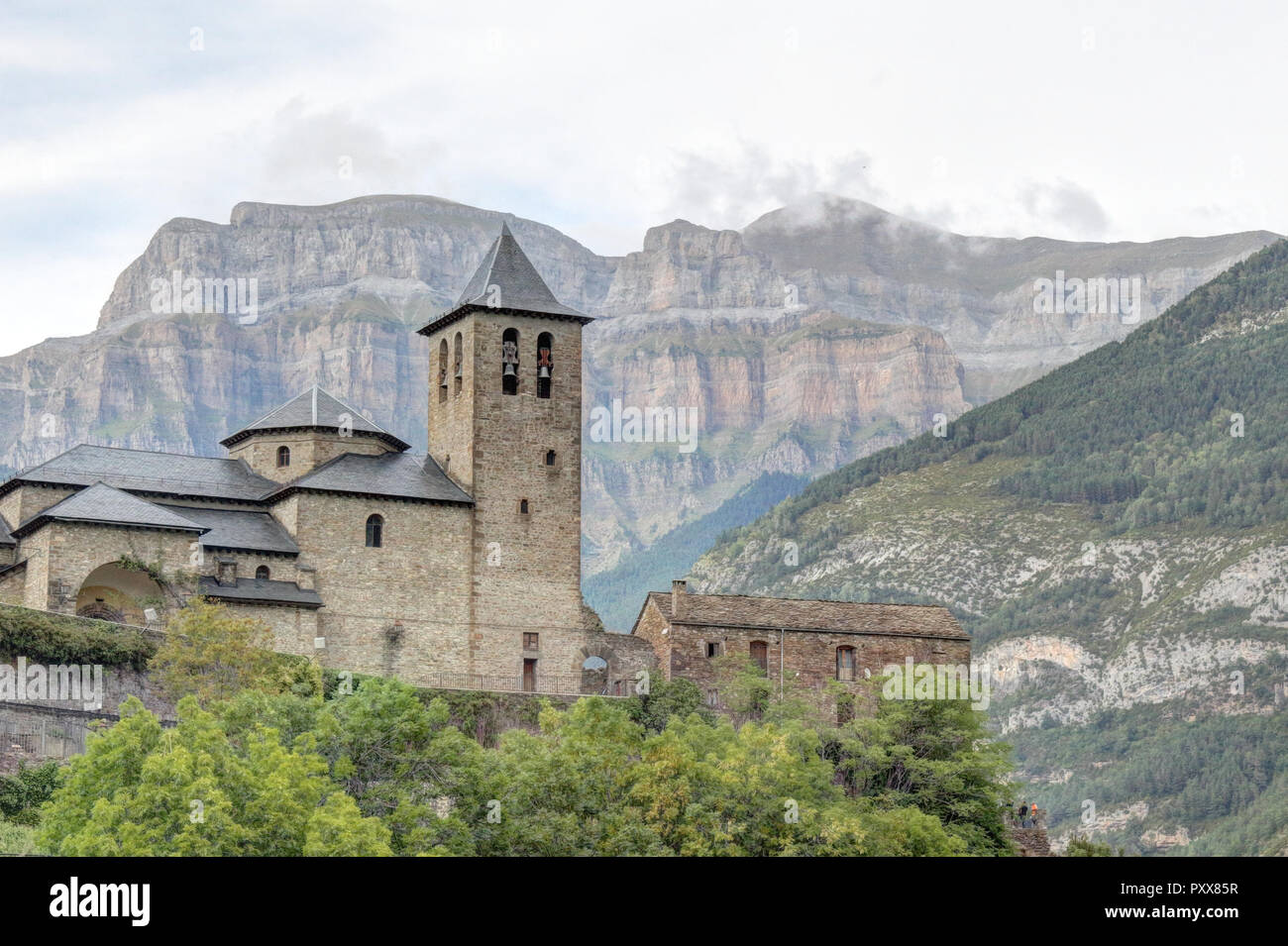 The rural small town of Torla, in the Aragon Pyrenees mountains in Spain, the romanesque church and the Pico Mondarruego range, at sunset Stock Photo