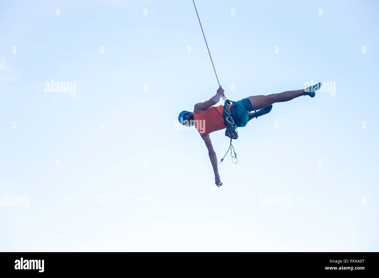 View of man in hardhat hanging on rope while doing rappel and showing ...