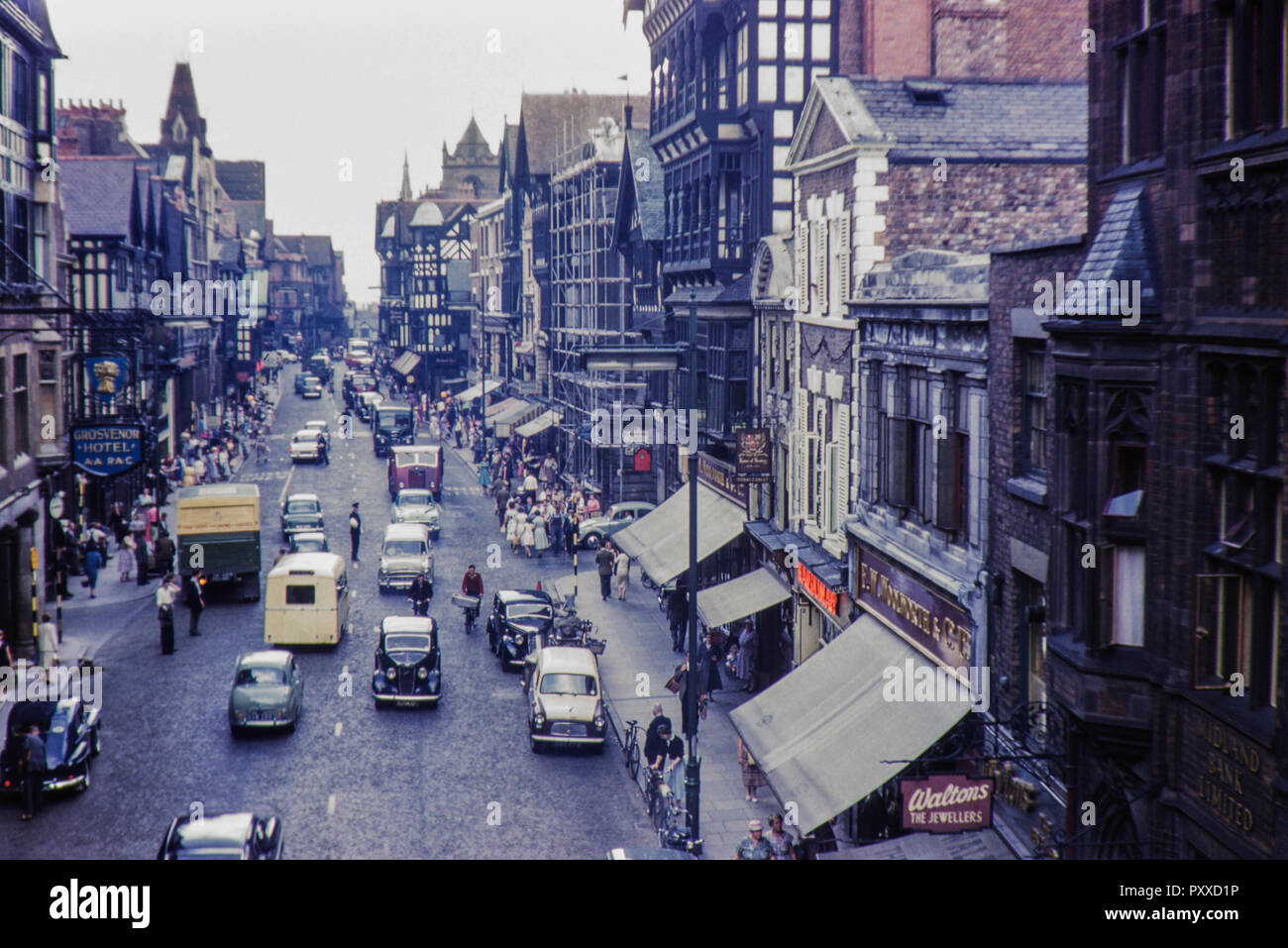 Busy scene on Eastgate Street, Chester city centre with the Woolworths store displaying the old livery. Note the policeman in the middle of the road on traffic duty. Image taken in 1959 Stock Photo