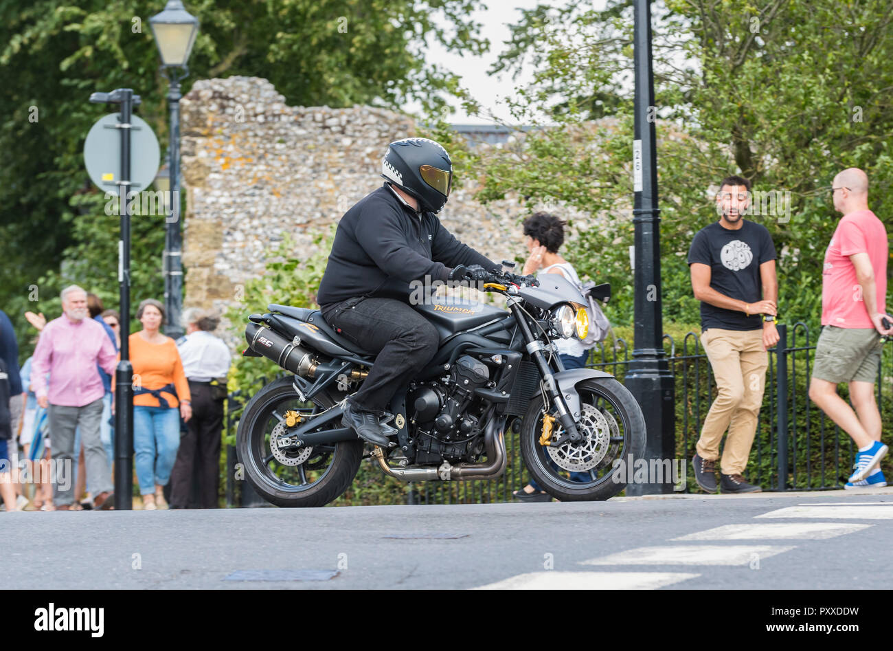 Overweight man on a Triumph motorcycle in the UK. Fat man riding motorbike. Stock Photo