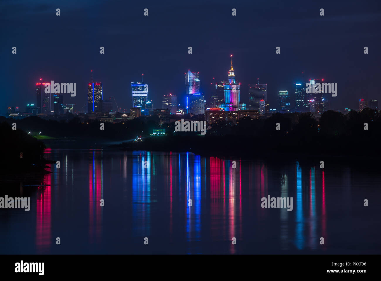 Night view on the Warsaw city buildings with lights reflection in the river. Stock Photo