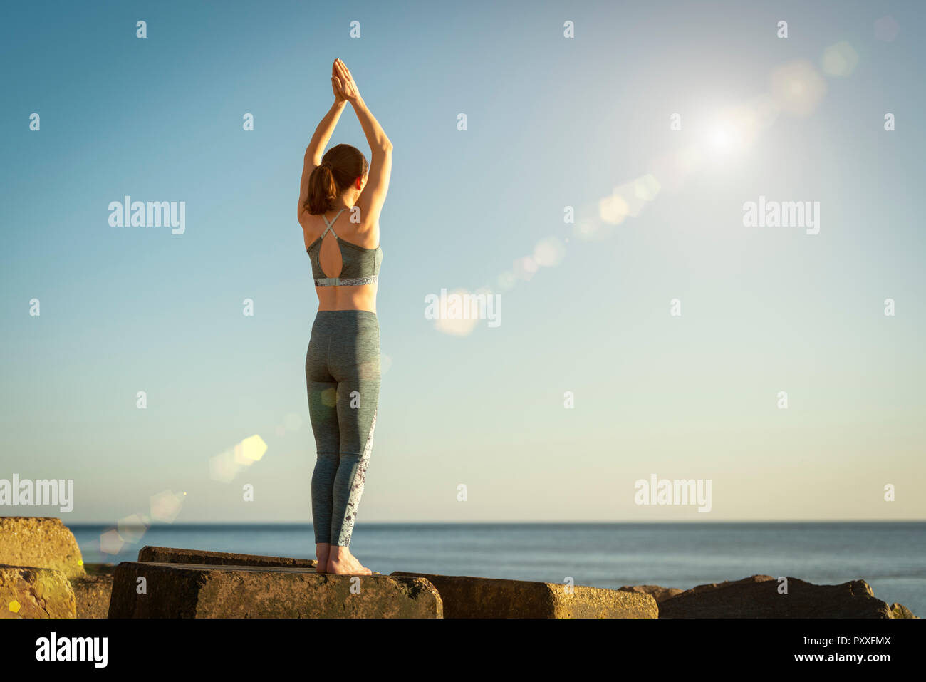 woman standing by the sea practicing yoga, tree pose Stock Photo - Alamy
