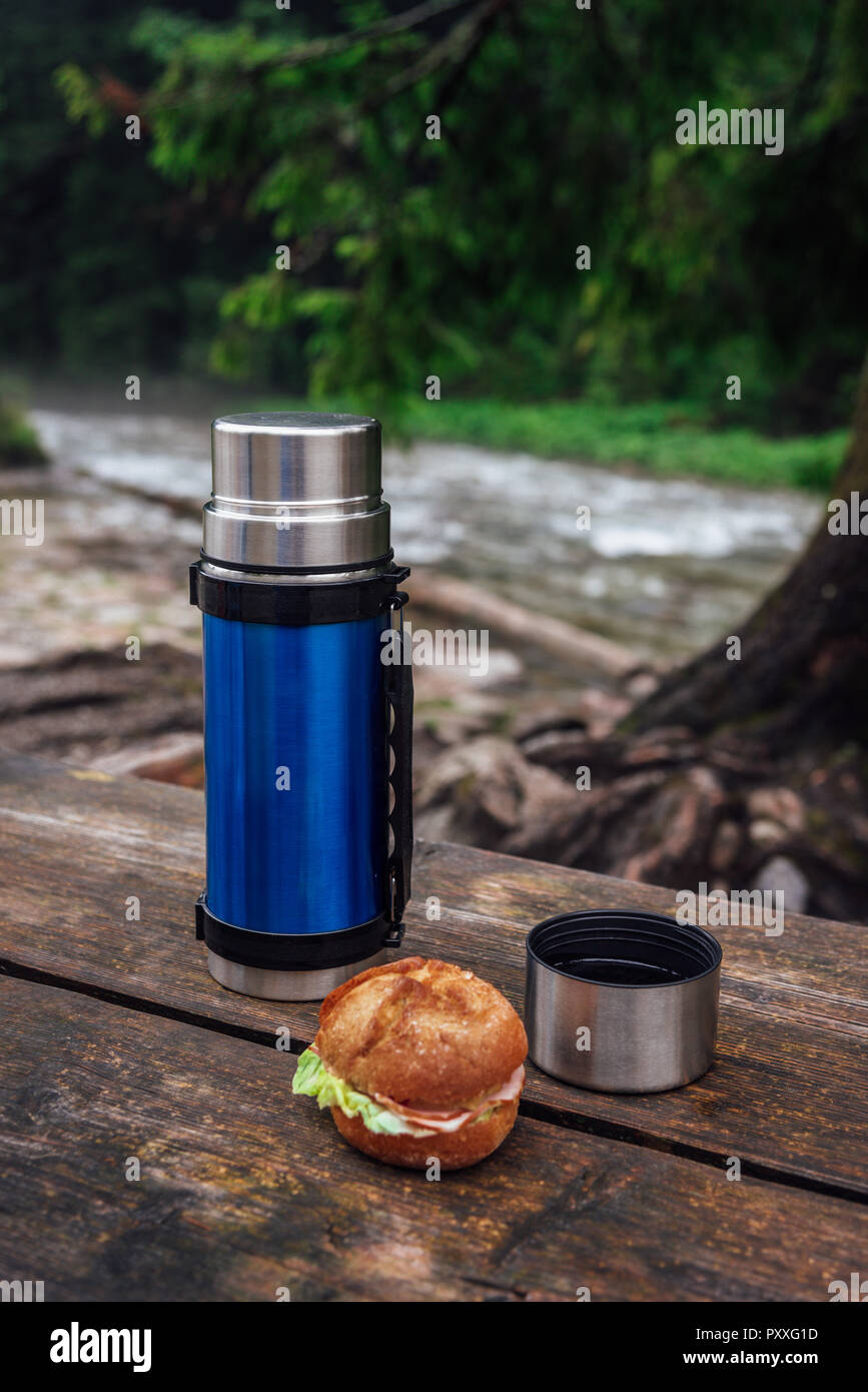 https://c8.alamy.com/comp/PXXG1D/view-on-the-blue-thermos-on-the-wooden-table-on-the-trekking-trail-break-for-hot-drink-PXXG1D.jpg