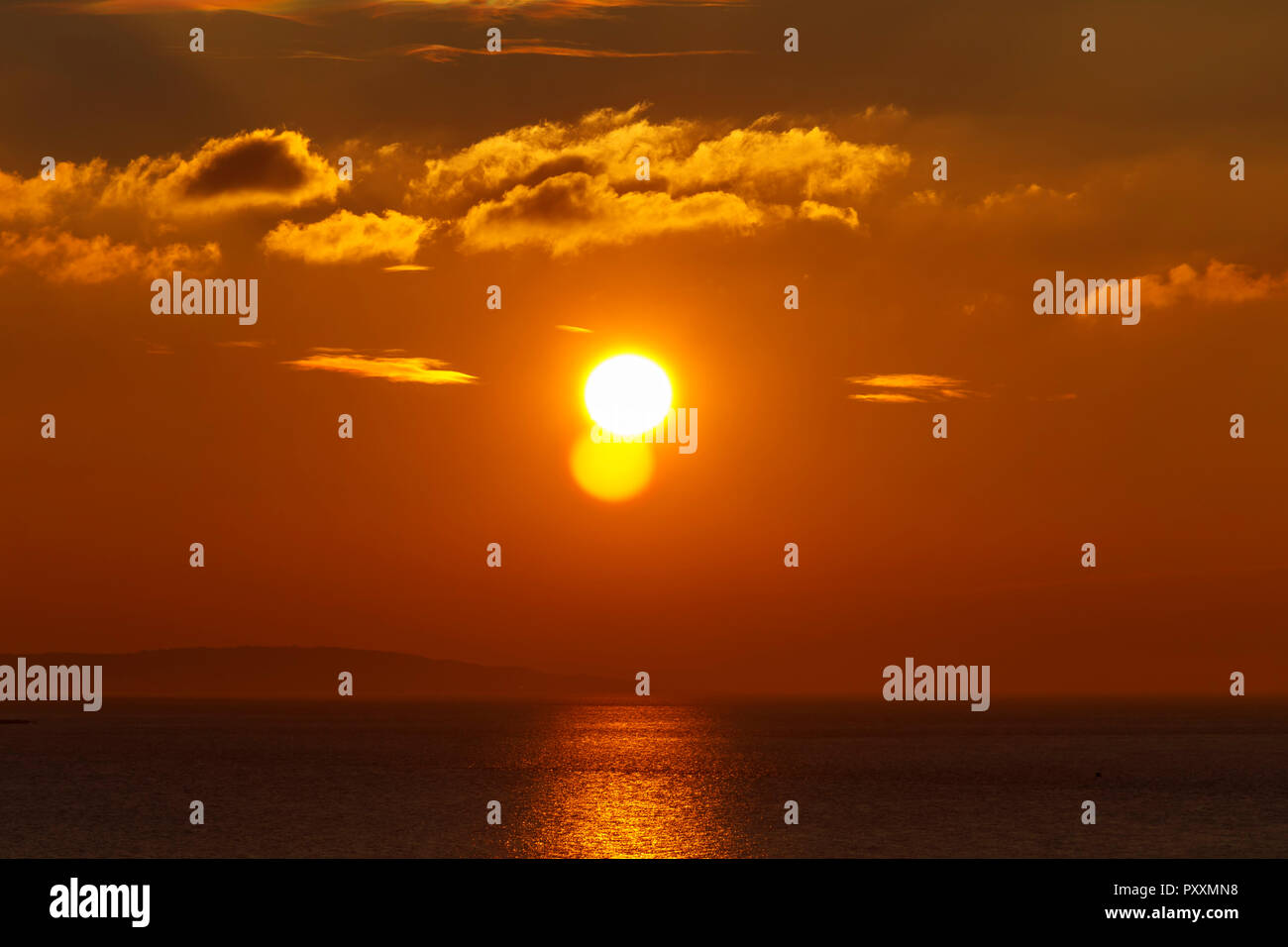 The bright sun sending a streak of sunlight across the sea Stock Photo