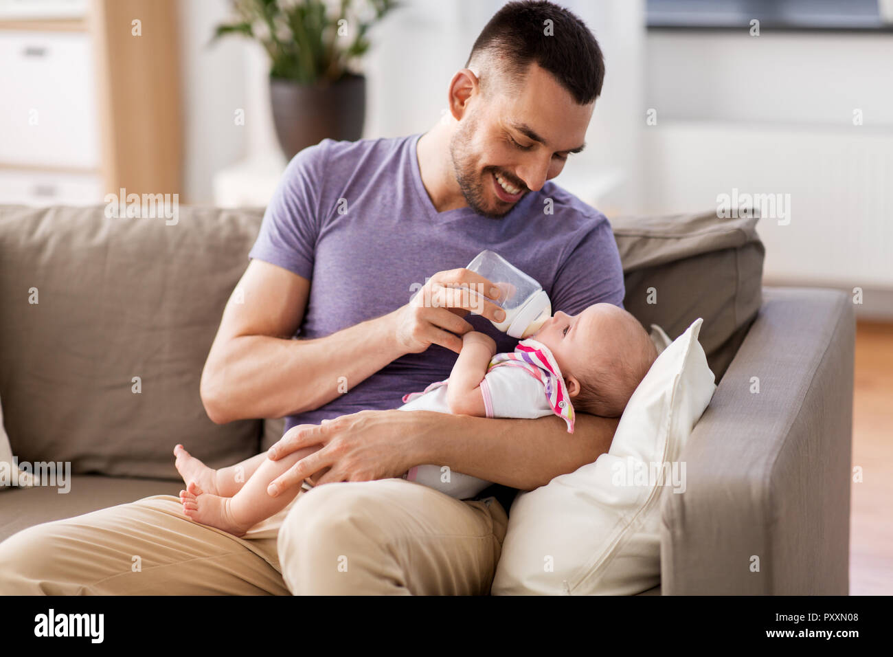 father feeding baby daughter from bottle at home Stock Photo