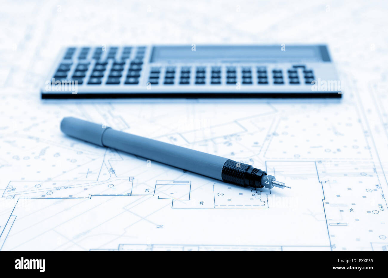 Architectural plans, calculator and drawing utensil. Picture in blue tone. Stock Photo